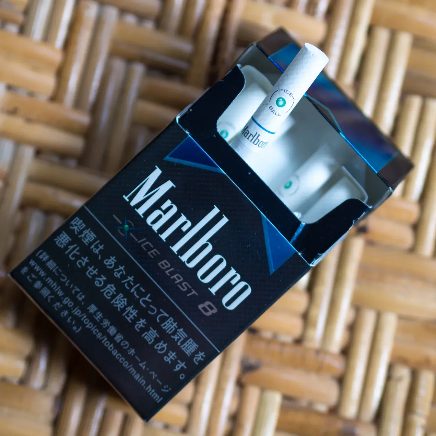 An opened Japanese Marlboro Ice Blast pack with a capsule cigarette pulled out, the filter marked ICE BALL with a green capsule dot