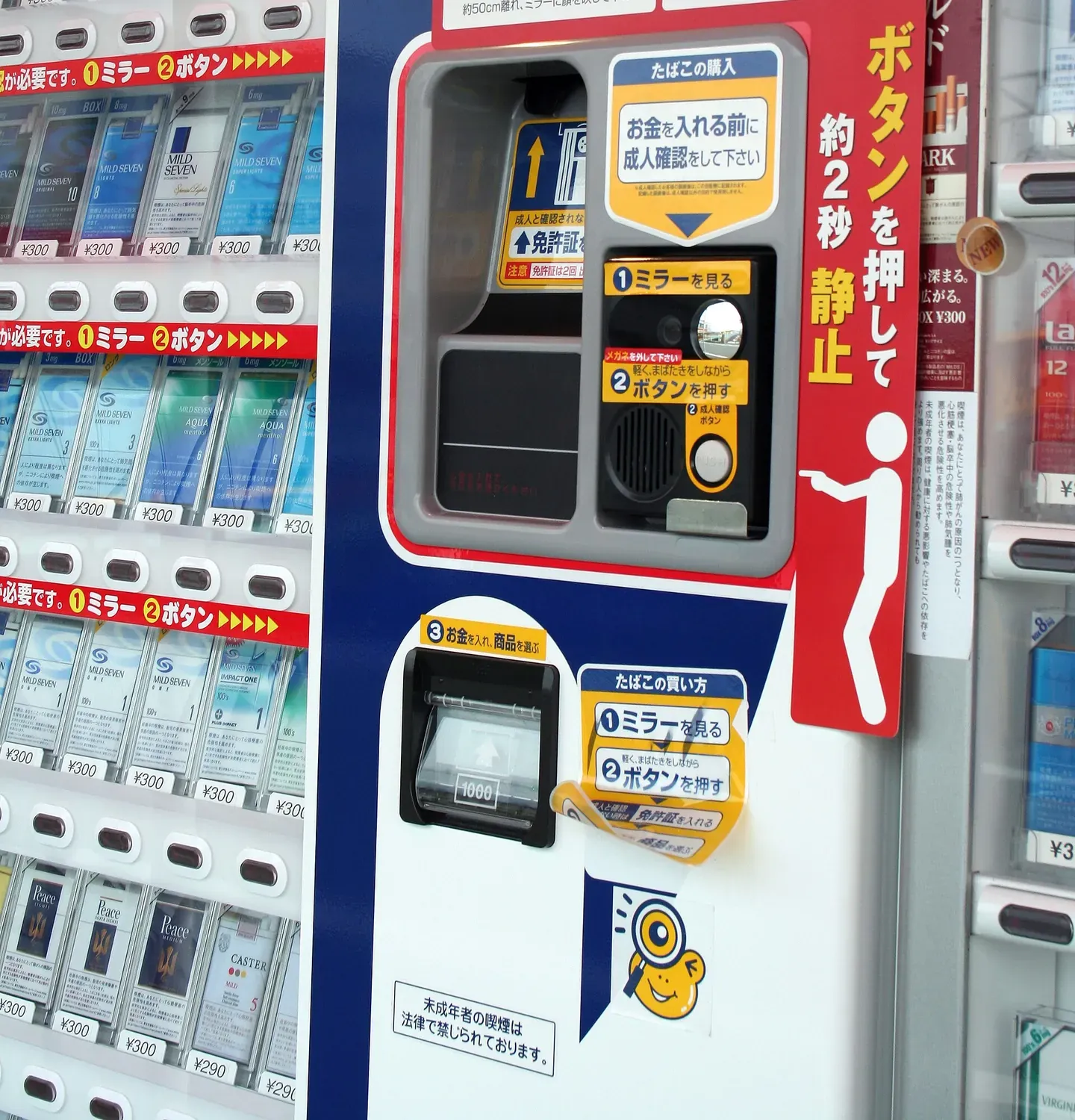 Anweisungen und Kameraeinheit für eine Altersprüfung per Gesichtserkennung an einem japanischen Zigarettenautomaten mit Spiegel und Bestätigungstaste