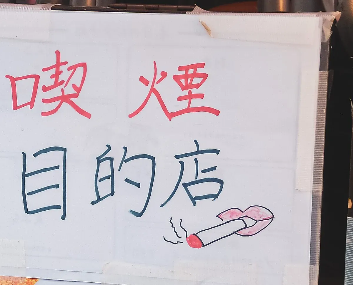 东京Kanda一家酒吧入口处贴着手写的“喫煙目的店”吸烟场所标识,旁边画有一支点燃的香烟