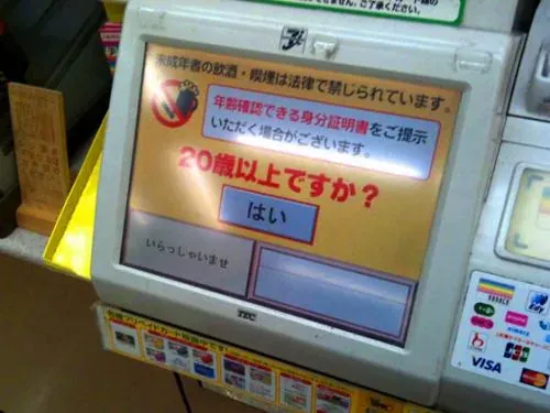 日本便利店收银台的年龄验证触屏,询问顾客是否已满20岁,画面只有一个“是”按钮,并提示可能要求出示带照片的身份证件