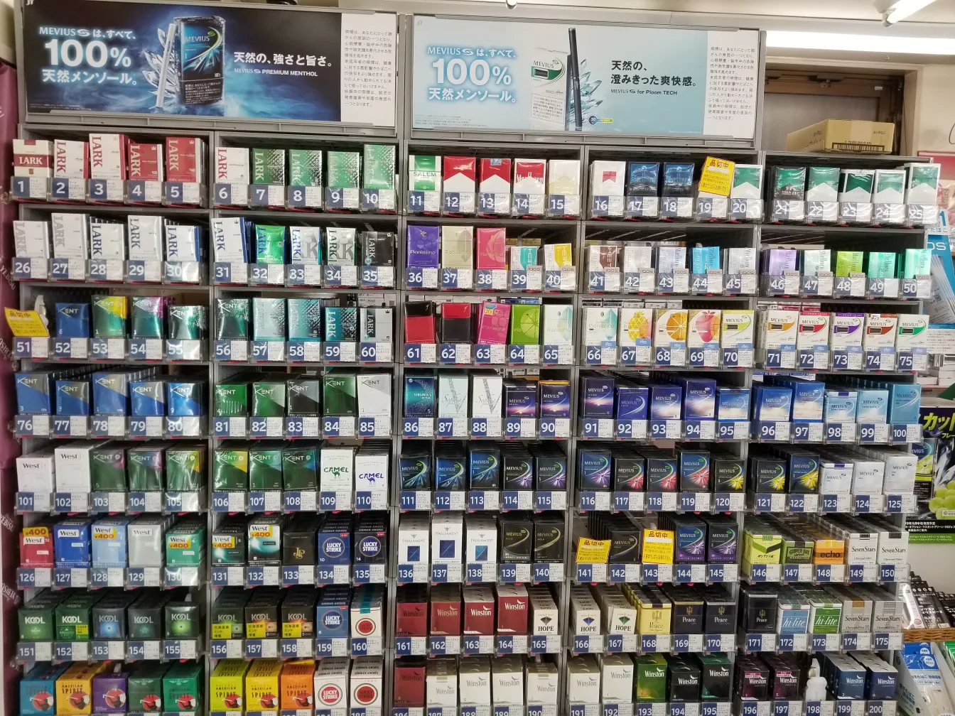 Several Japanese cigarette packs on a counter, including Mevius, Seven Stars and Peace