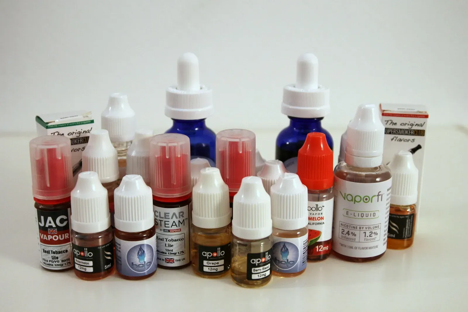 An assortment of e-liquid bottles from several brands, their labels showing nicotine strengths in milligrams and bottle volumes in millilitres — the figures Japan's 120ml personal import limit is measured against