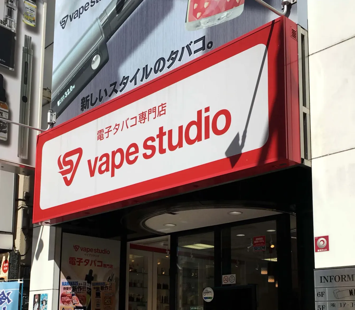 Fassade eines E-Zigaretten-Fachgeschäfts von VAPE Studio in Ikebukuro, Tokyo, mit rotem Schild „電子タバコ専門店“; im Inneren sind Regale mit E-Liquids zu sehen