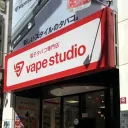 东京池袋一家 VAPE Studio 电子烟专卖店的店面，红色招牌写着“電子タバコ専門店”，店内可见陈列电子烟烟油的货架