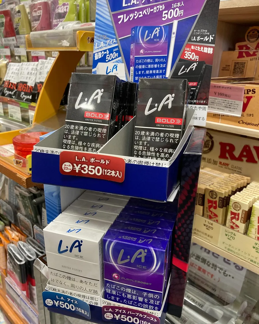 L.A. 크레텍 필터 담배 진열 — L.A. Bold, L.A. Ice, L.A. Ice Purple Boost — 그리고 그 옆의 RAW 롤링 페이퍼 — Blue Lace, Ikoma
