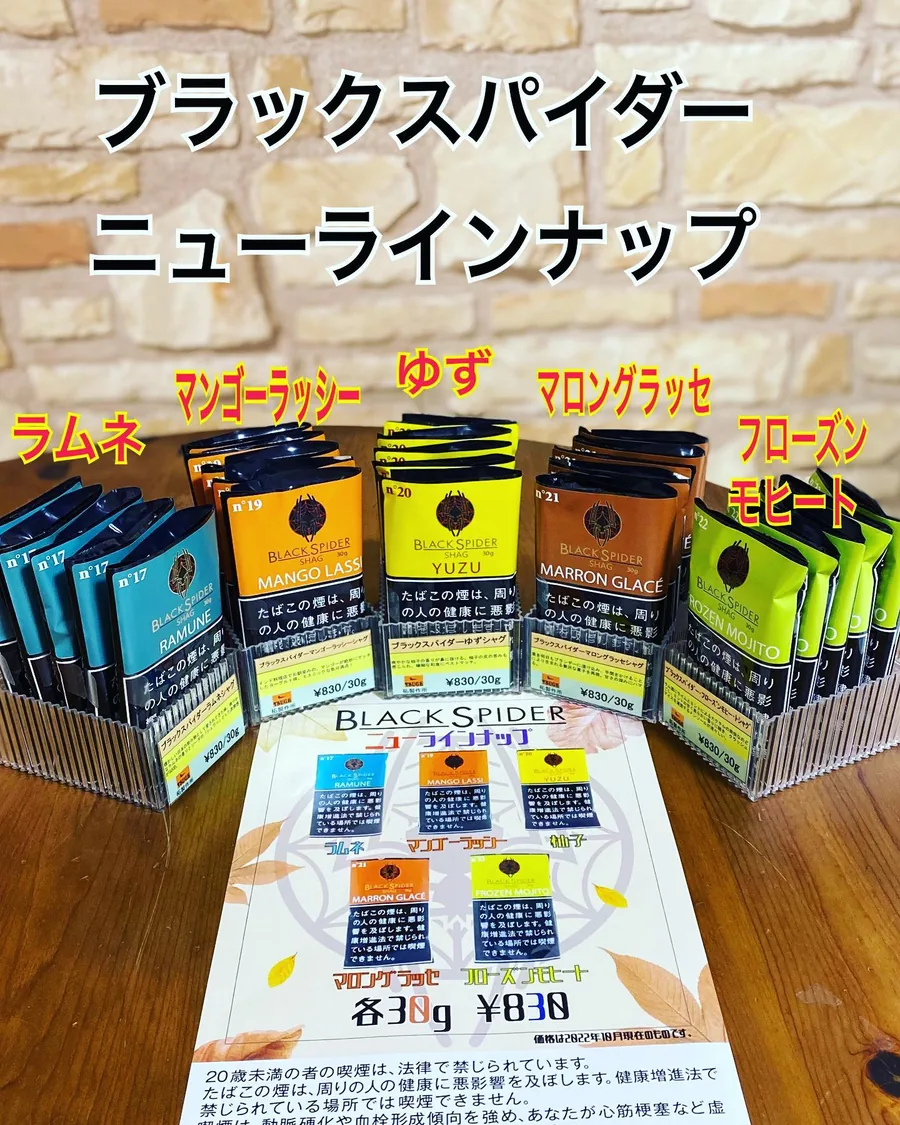 30 g 파우치로 나온 Black Spider Shag 신제품 라인업 — Ramune, Mango Lassi, Yuzu, Marron Glacé, Frozen Mojito — 앞에는 ブラックスパイダー ニューラインナップ 포스터 — Himawari Tobacco Shop, Tsuruga