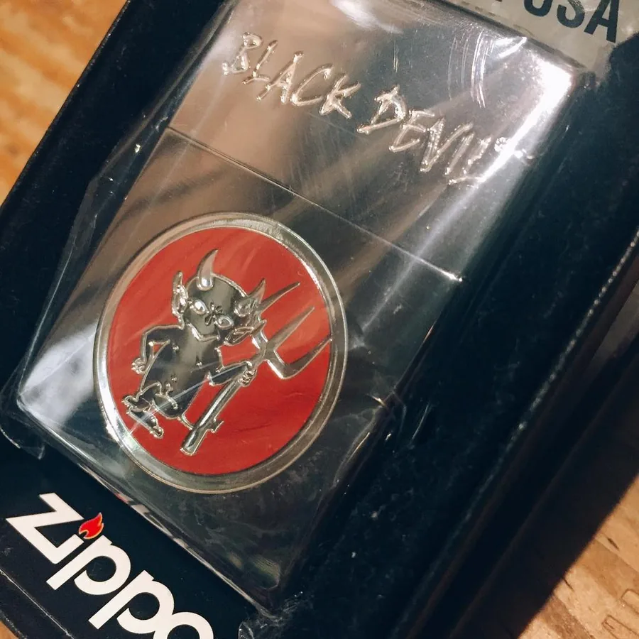 상자에 담긴 Black Devil Zippo 라이터 — 케이스에 “BLACK DEVIL”이 새겨져 있고 그 위에 붉은 에나멜 악마가 있습니다. 가게의 2017년 10월 게시글에는 재고가 있다고 적혀 있습니다 — Shop Kita, Kawagoe