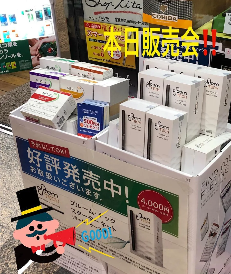 가게 앞에 진열된 Ploom Tech 스타터 키트와 Mevius 리필 팩. ショップきた, 営業時間 AM10:00〜PM8:00(당시의 영업시간)이라고 적힌 간판, Cohiba 간판, 가게의 “오늘 판매회”(本日販売会) 글씨도 보입니다. 2018년 4월 — Shop Kita, Kawagoe